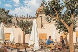 una pareja sentada en una mesa frente a un edificio en Hotel Bodega Tio Pepe en Jerez de la Frontera