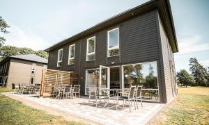 une maison noire avec des chaises et des tables sur une terrasse dans l'établissement Saxnäs Ferieboende L. Erik, à Färjestaden