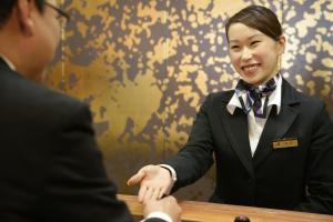 Uma mulher de smoking a apertar a mão a um homem. em Hotel New Carina em Morioka