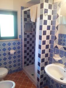 een blauwe betegelde badkamer met een wastafel en een douche bij Villa Loco in Capo Vaticano