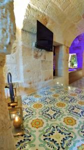 a room with a tile floor with a tv on a wall at My Monopoli - Casa dei Fiori Suite "Mimosa" Casa d'epoca in Monopoli