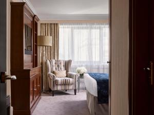 um quarto de hotel com uma cama e uma cadeira e uma janela em InterContinental London Park Lane, an IHG Hotel em Londres