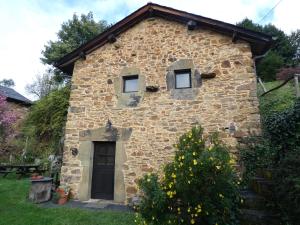 un pequeño edificio de piedra con 2 ventanas y una puerta en El Observatoriu, en Muñás