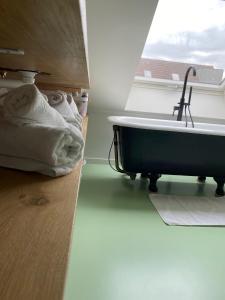 a bathroom with a bath tub sitting next to a window at Lichtrijke loft bij restaurant Den Olifant in Ypres