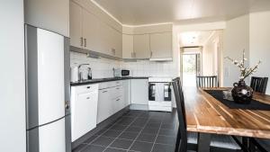 a kitchen with white cabinets and a wooden table at Saxnäs Ferieboende L Clara in Färjestaden