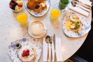 een tafel met borden ontbijtproducten en glazen sinaasappelsap bij Hotel Indigo The Hague - Palace Noordeinde, an IHG Hotel in Den Haag