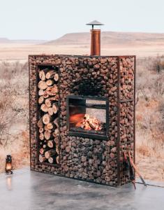 Eco Karoo Mountain Lodge في Luckhoff: موقد مصنوع من الخشب مع النار