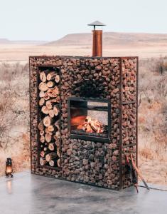 a fireplace made out of logs with a fire at Eco Karoo Mountain Lodge in Luckhoff