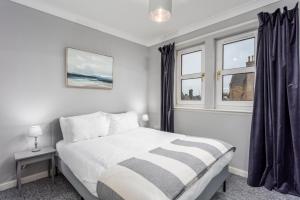 a bedroom with a bed and two windows at Millbrae Residence - Donnini Apartments in Ayr