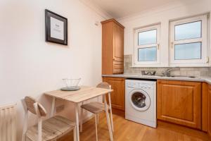 a kitchen with a table and a washing machine at Millbrae Residence - Donnini Apartments in Ayr