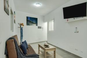ein Wohnzimmer mit einem Sofa und einem TV an der Wand in der Unterkunft 2b El Amore in Vecindario