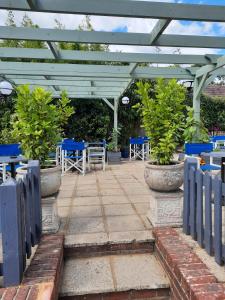 a patio with blue tables and chairs and a white pergola at The Labouring Man in Coldwaltham