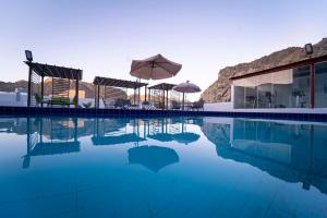 a pool with chairs and umbrellas next to a building at Riyam Hotel in Muscat