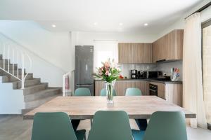 a dining room table with chairs and a vase of flowers at Lux Villa Nymphes Dioni, 30m from beach with Pool, BBQ and Play Area in Stavromenos