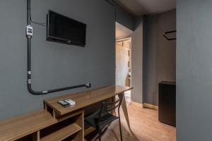 a room with a desk and a tv on the wall at OYO Hotel Massimo Brooklin, Sao Paulo in Sao Paulo