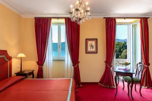 a bedroom with red curtains and a chandelier at Grand Hotel Majestic in Verbania