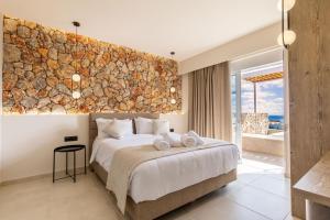 a bedroom with a large bed and a stone wall at Venezia Luxury Living Villas, Faliraki in Faliraki