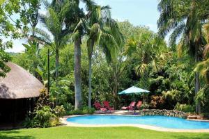 a resort swimming pool with two chairs and an umbrella at Idle & Wild Chalet in Hazyview