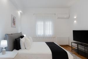 ein weißes Schlafzimmer mit einem Bett und einem Flachbild-TV in der Unterkunft Kolonaki Luxury Residence in Athen