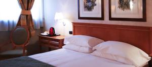 1 dormitorio con cama con cabecero de madera y escritorio en Monica Hotel Fiera en Pregnana Milanese