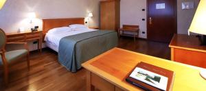 Habitación de hotel con cama, escritorio y mesa. en Monica Hotel Fiera en Pregnana Milanese