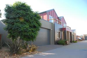 a house with a garage door and a tree at The Lakes Apartments in Lakes Entrance