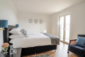 a white bedroom with a bed and a chair at Casa Katrida in Selca