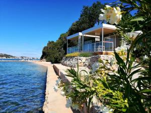 a house on the shore of a beach with flowers at Olivia Green Camping in Tisno