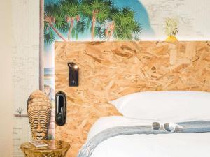 a bedroom with a bed with a mural of palm trees at ibis Styles Paris Boulogne Marcel Sembat in Boulogne-Billancourt
