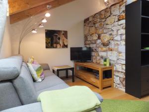 a living room with a couch and a stone wall at Ferienwohnung Alpenstern in Rieden am Forggensee