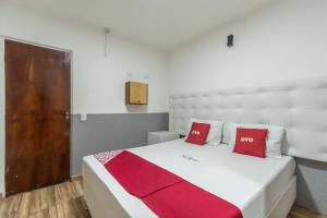 um quarto com uma grande cama branca com almofadas vermelhas em OYO Hotel San Remo, São Paulo em São Paulo