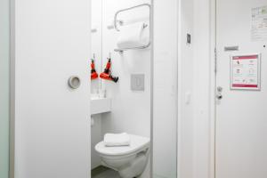 a white bathroom with a toilet and a shower at Omena Hotel Helsinki Lönnrotinkatu in Helsinki
