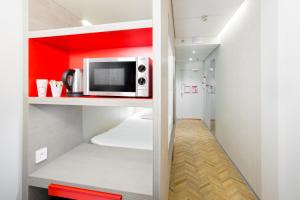 a kitchen with a microwave on a red shelf at Omena Hotel Helsinki Lönnrotinkatu in Helsinki