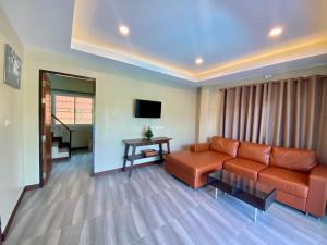 a living room with a couch and a television at Blue Aura Pool Villa in Nai Yang Beach