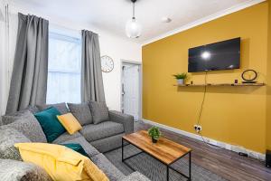 ein Wohnzimmer mit einem Sofa und einem TV an einer gelben Wand in der Unterkunft The Great North Hill - TV in Every Bedroom! in Swansea
