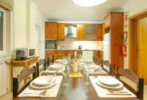 uma cozinha com uma mesa longa com pratos e copos de vinho em Baleal Sunset Residence no Baleal