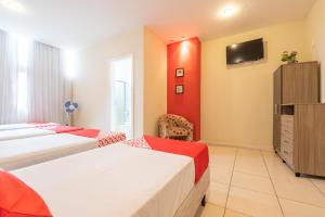 a hotel room with two beds and a tv at OYO Hotel L'Espace - Jaraguá Belo Horizonte in Belo Horizonte