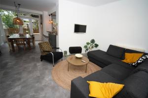 a living room with a black couch and a table at Vakantiehuis Le Platane - in natuurgebied nabij Nijmegen in Beek