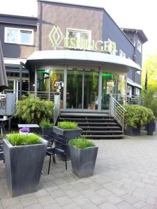 a restaurant with chairs and plants in front of a building at Wessinger in Neu Isenburg