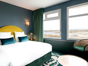 a hotel room with a bed and two windows at Hotel Mercure Roscoff Bord De Mer in Roscoff