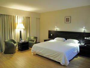 a hotel room with a large bed and two chairs at Labuk Hotel in Sandakan