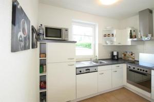 a kitchen with white cabinets and a microwave at Hanne-Hus-913 in Kühlungsborn