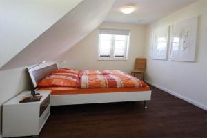 a bedroom with a bed with an orange comforter and two windows at Hanne-Hus-913 in Kühlungsborn