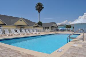 a swimming pool with chairs and a palm tree at Travelodge by Wyndham Panama City Beach / Beachfront in Panama City Beach