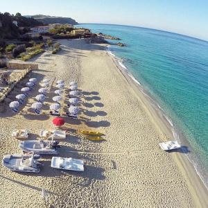 einen Strand mit Liegestühlen und Sonnenschirmen und dem Meer in der Unterkunft Costa degli Dei Resort in Capo Vaticano