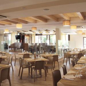 ein Esszimmer mit Tischen, Stühlen und Fenstern in der Unterkunft Costa degli Dei Resort in Capo Vaticano