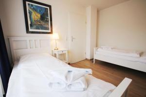 キュールングスボルンにあるStrandschloesschen-Haus-I-WE-13-9890の白いベッドルーム(ベッド1台、ランプ付きテーブル付)