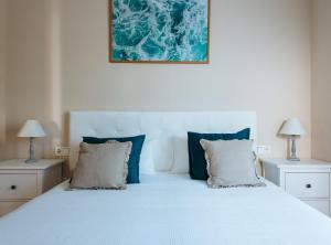 a bedroom with a white bed with blue pillows at Nice Apartment next to Plaza de Armas in Seville