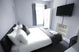 a bedroom with a white bed and a flat screen tv at Honest Hospital House Apartment 1 in Southampton