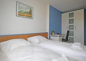 キュールングスボルンにあるStrandschloesschen-I-WE-15-9912のベッドルーム1室(白いベッド1台、テーブル、写真付)